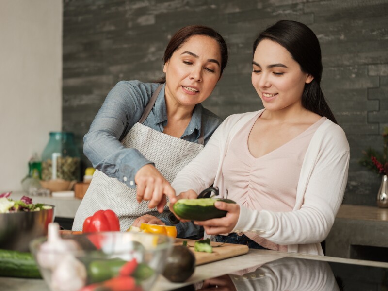 Latin mother and daughter preparing meal together at home