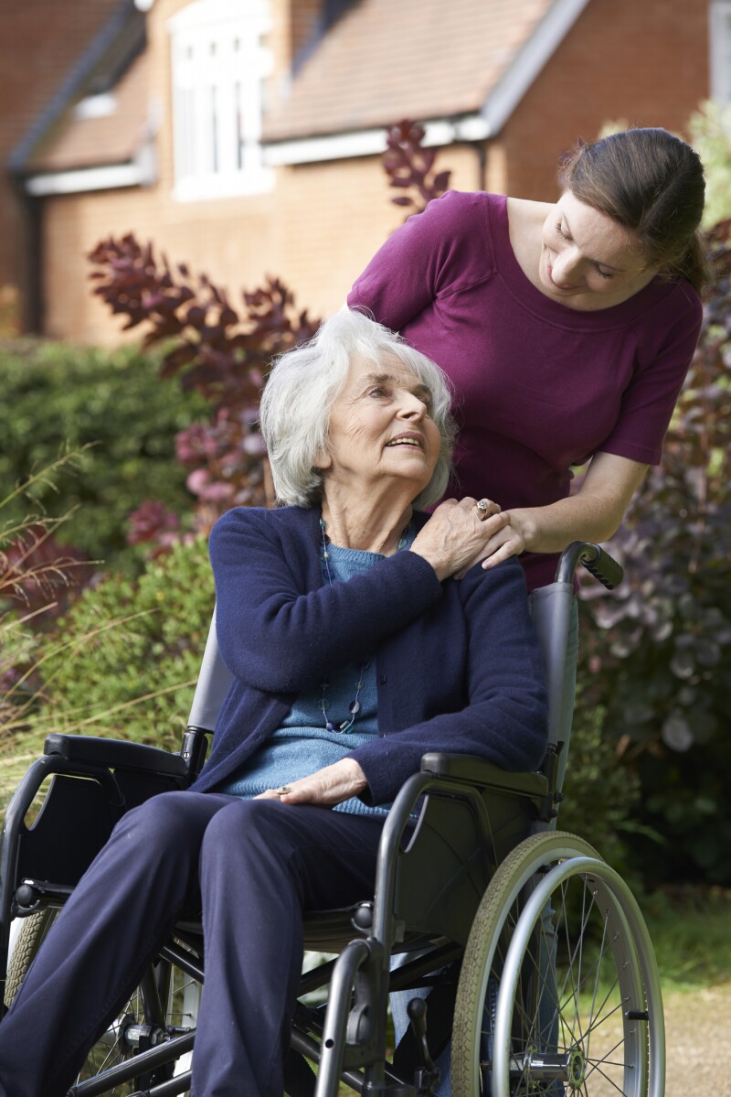 Daughter Pushing Senior Mother In Wheelchair
