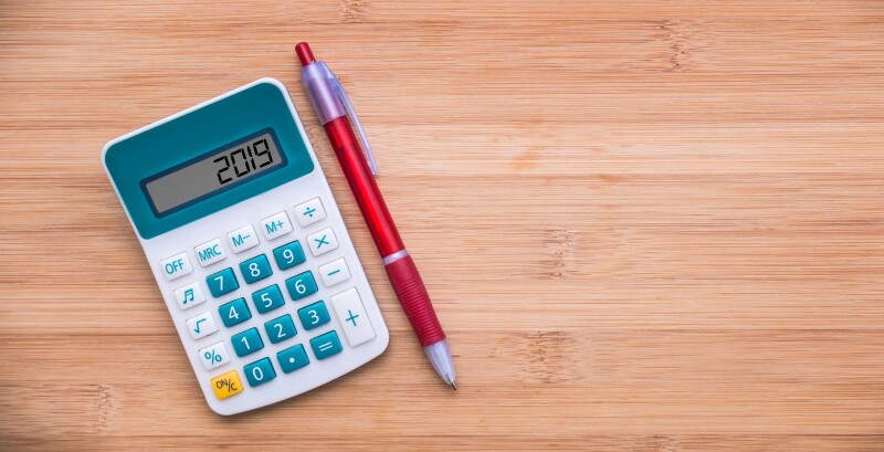 2019 written on a calculator and a pen on wooden background