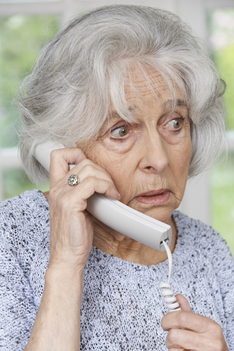 Worried Senior Woman Answering Telephone At Home