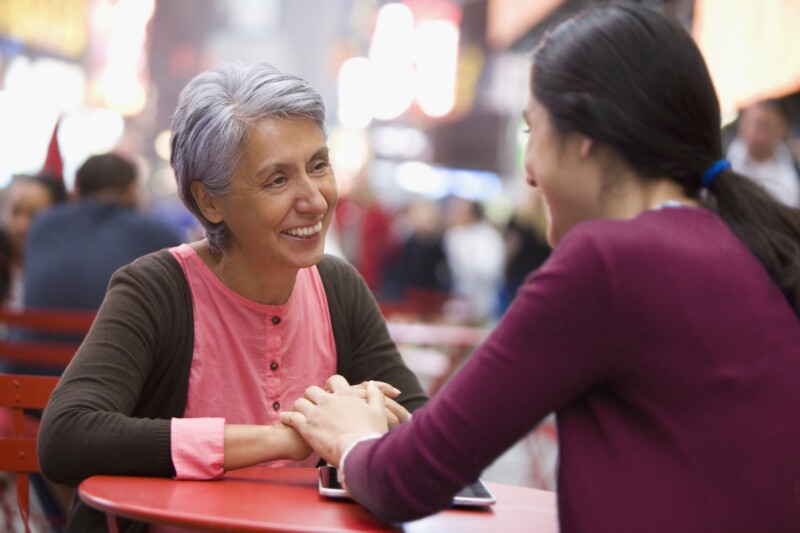 Hispanic mother and daughter sitting at cafe
