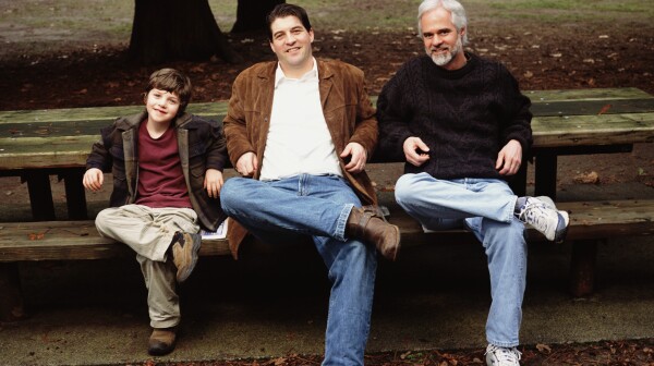 Grandfather, father and son (5-7) sitting on park bench, portrait