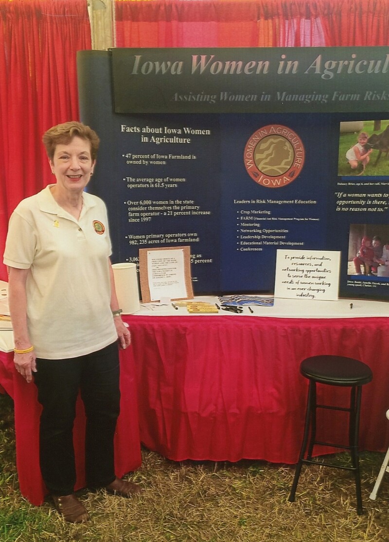 A woman standing in front of a booth with a posterboard