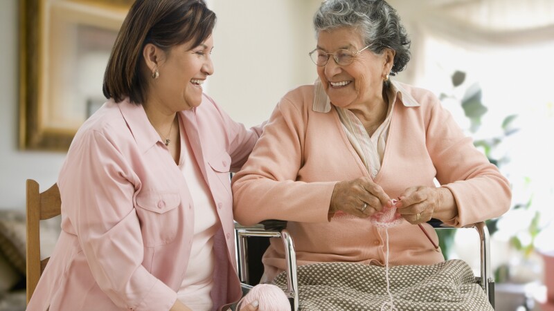 Senior Hispanic woman knitting with adult daughter