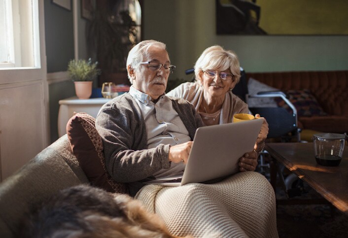 Older man and woman use a laptop computer on the sofa.
