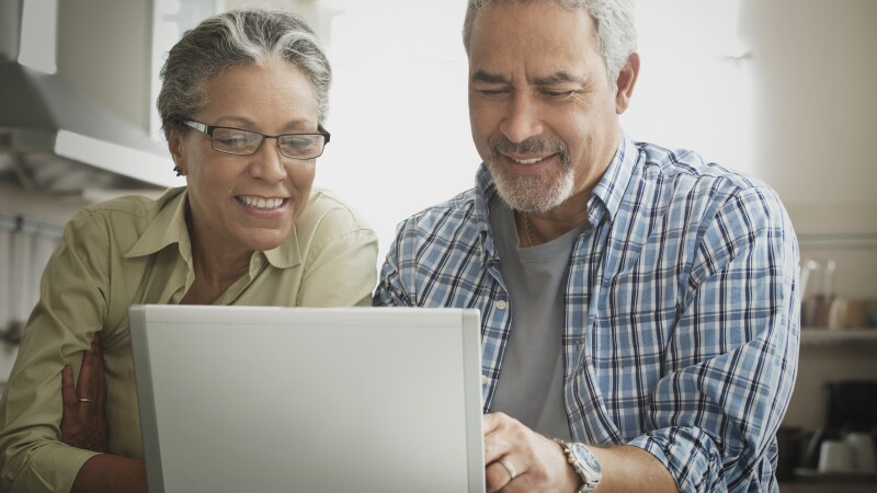 Hispanic couple using laptop in kitchen