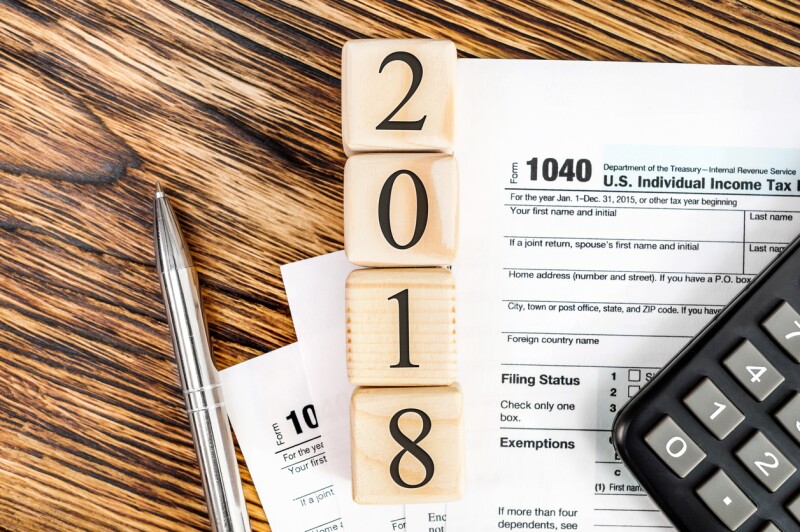 Pay tax in 2018 year concept. Numbers 2018 wit tax form 1040, calculator and pen on the table. Top view.