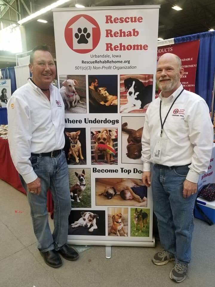 Two men in front of a standing poster for Rescue Rehab Rehome