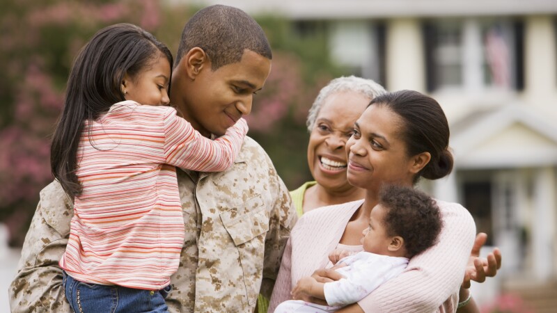 African American military father hugging family