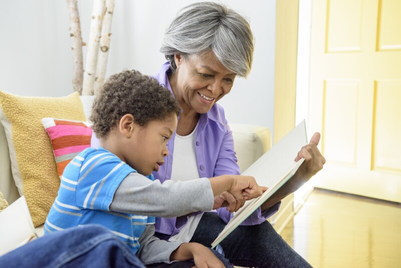 African American grandmother showing book to grandson, smiling