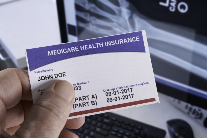 Medicare Health Insurance Card in medical office with Xray and hand holding