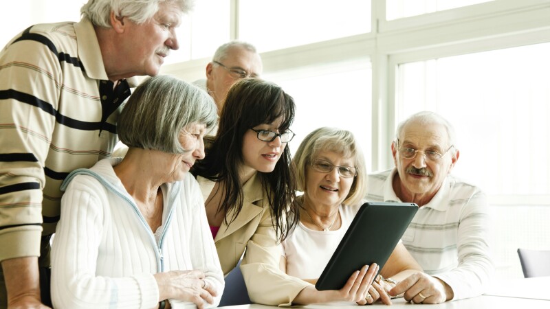 group of seniors at lecture examine tablet pc