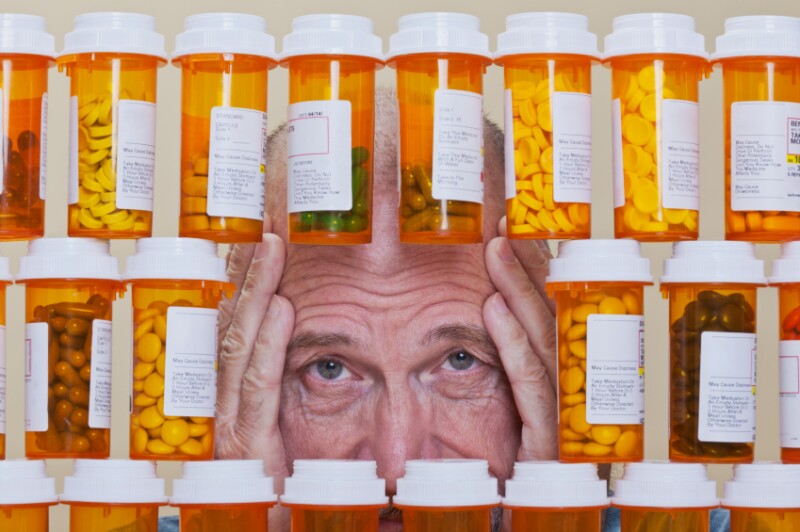 Depressed Senior Man Looking Through Rows of Prescription Medica