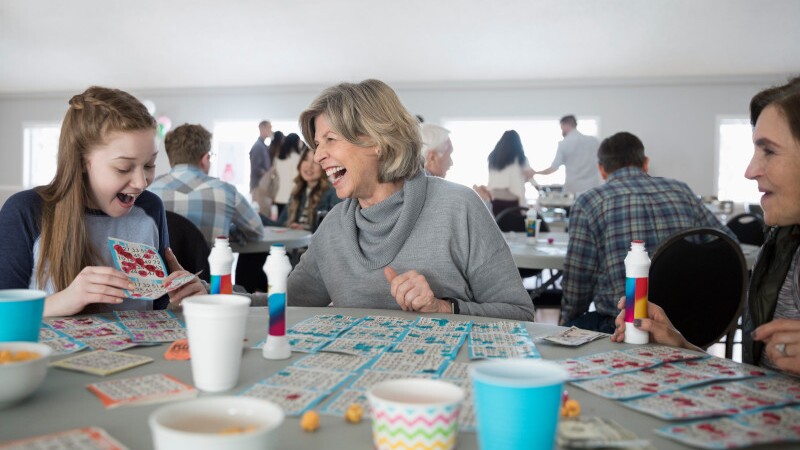 Laughing grandmother and granddaughter playing bingo at community center