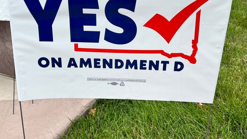 A white sign in a yard that says YES on Amendment D