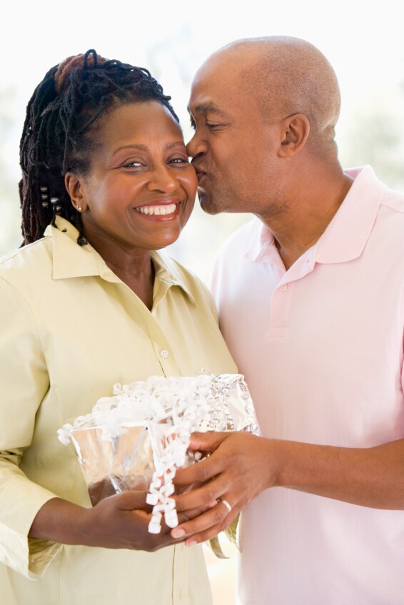 Husband and wife holding gift kissing and smiling