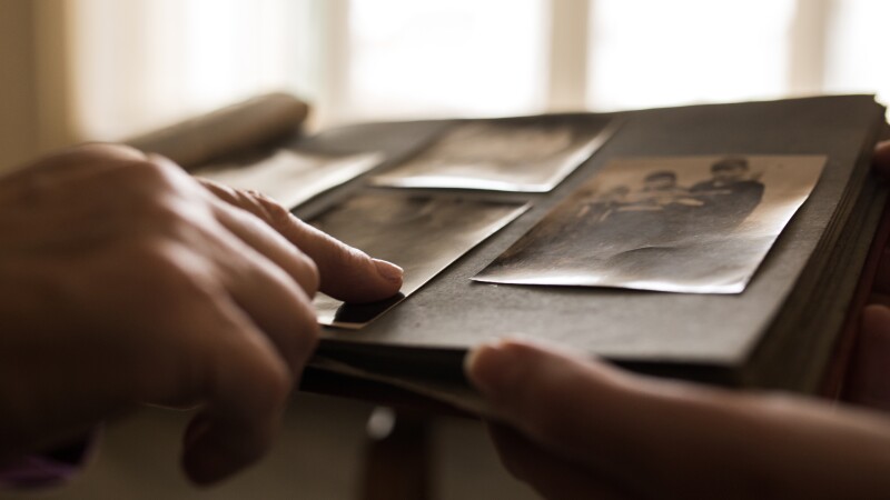 Close up human hand pointing to photo in photo album
