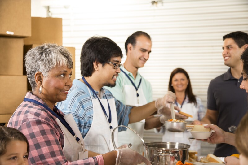 Group of volunteers serve food at community soup kitchen. Charity.