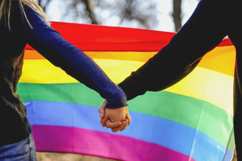 Two lesbian girls holding hands and rainbow flag