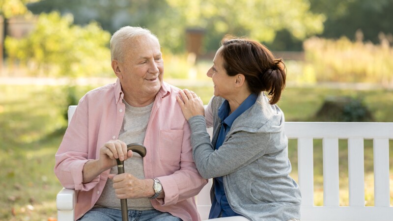 Caregiver and senior man in the park on park bench