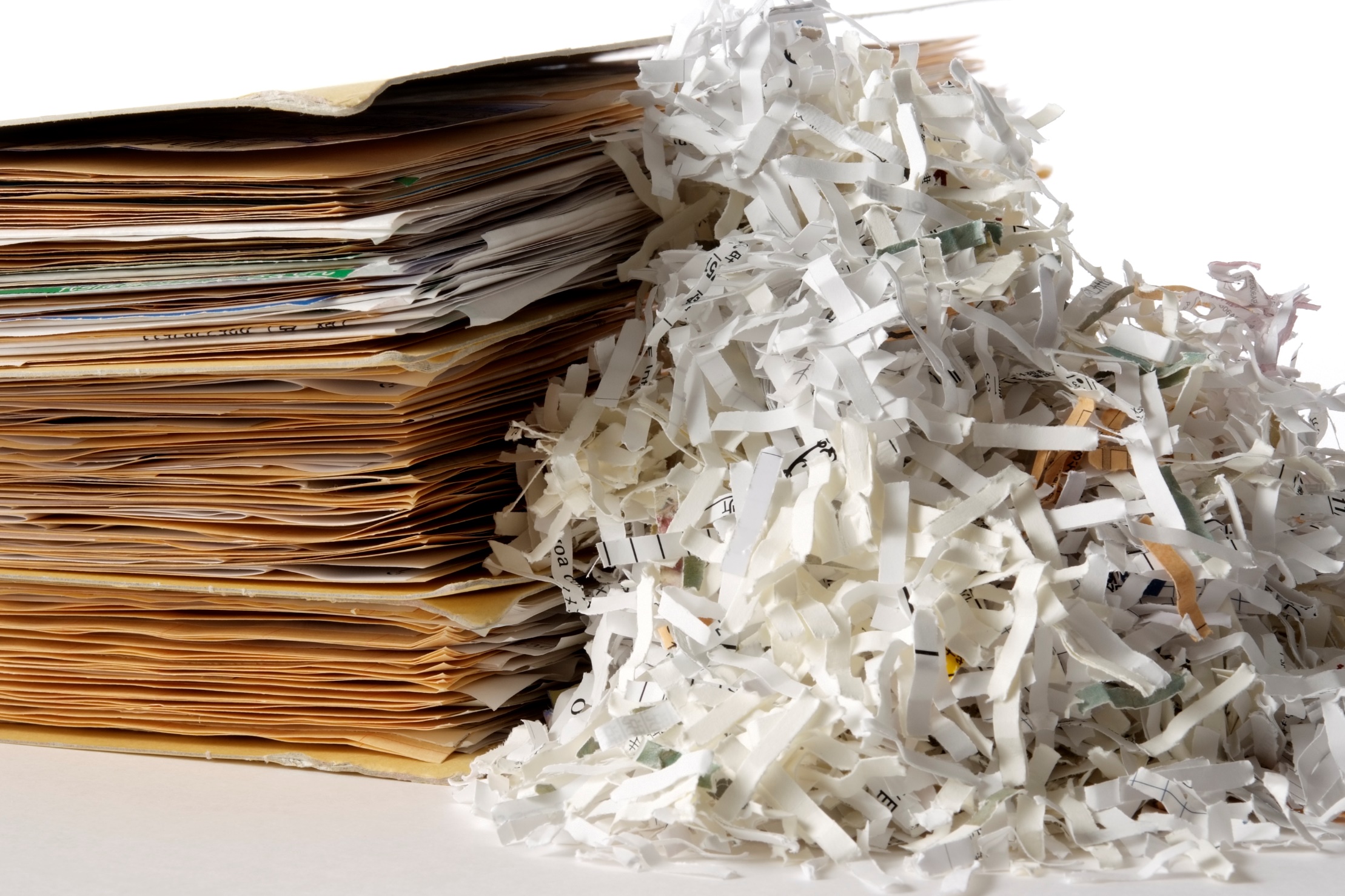 A pile of shredded paper next to a stack of file folders