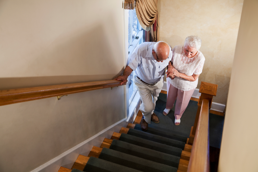 Senior woman helping husband climb staircase