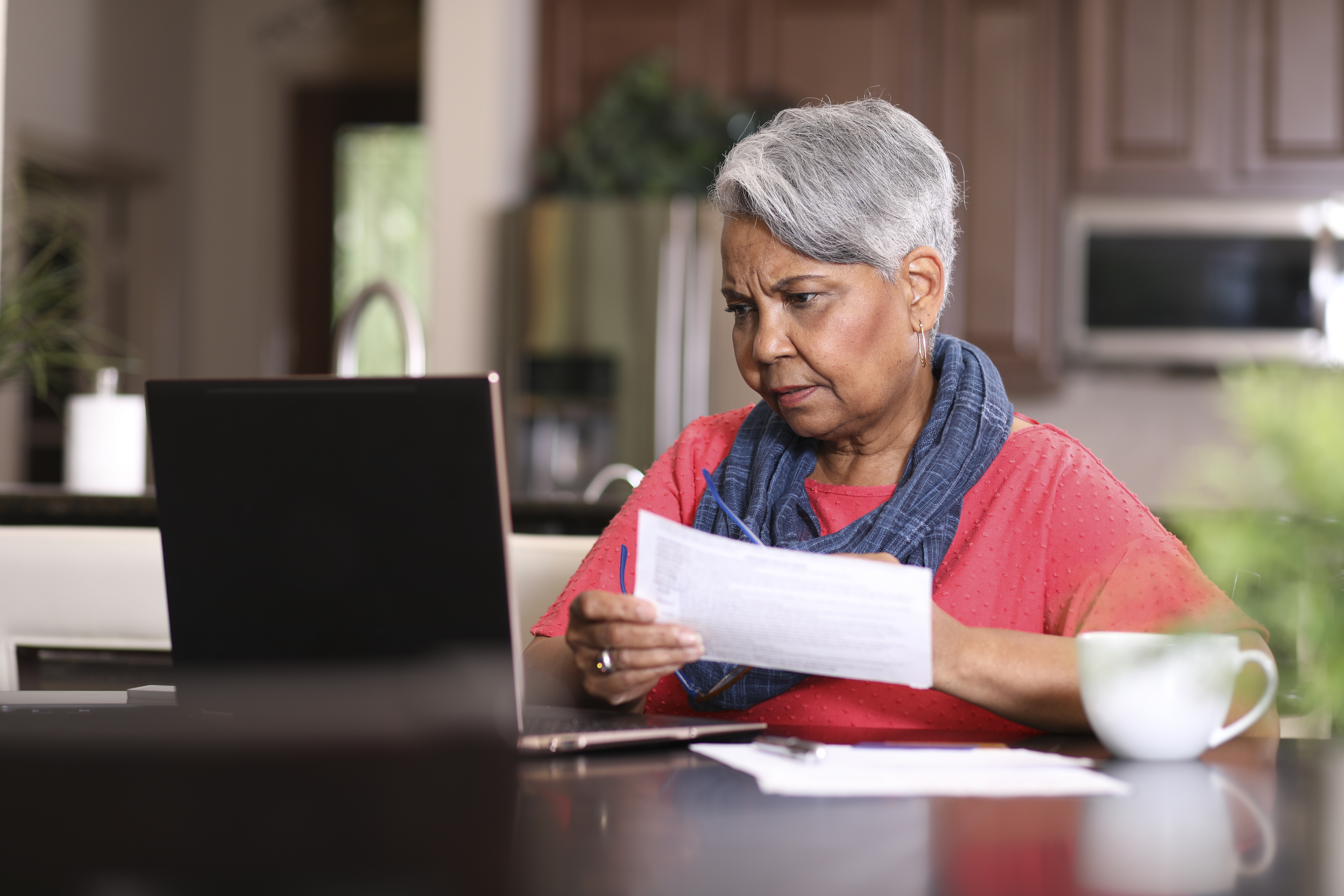 Senior adult woman frustrated paying bills at home.