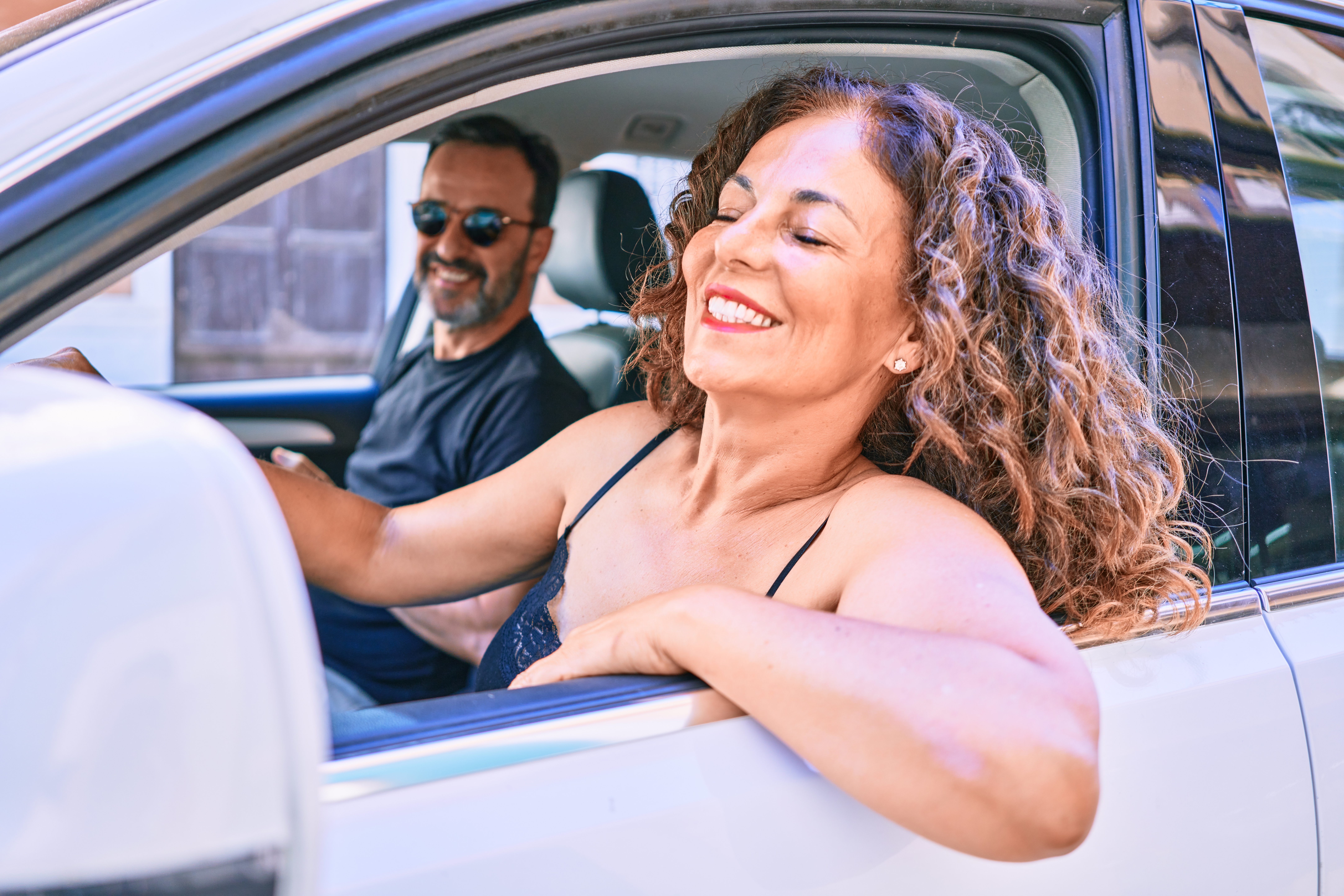 Middle age beautiful couple on vacation wearing sunglasses smiling happy driving car.