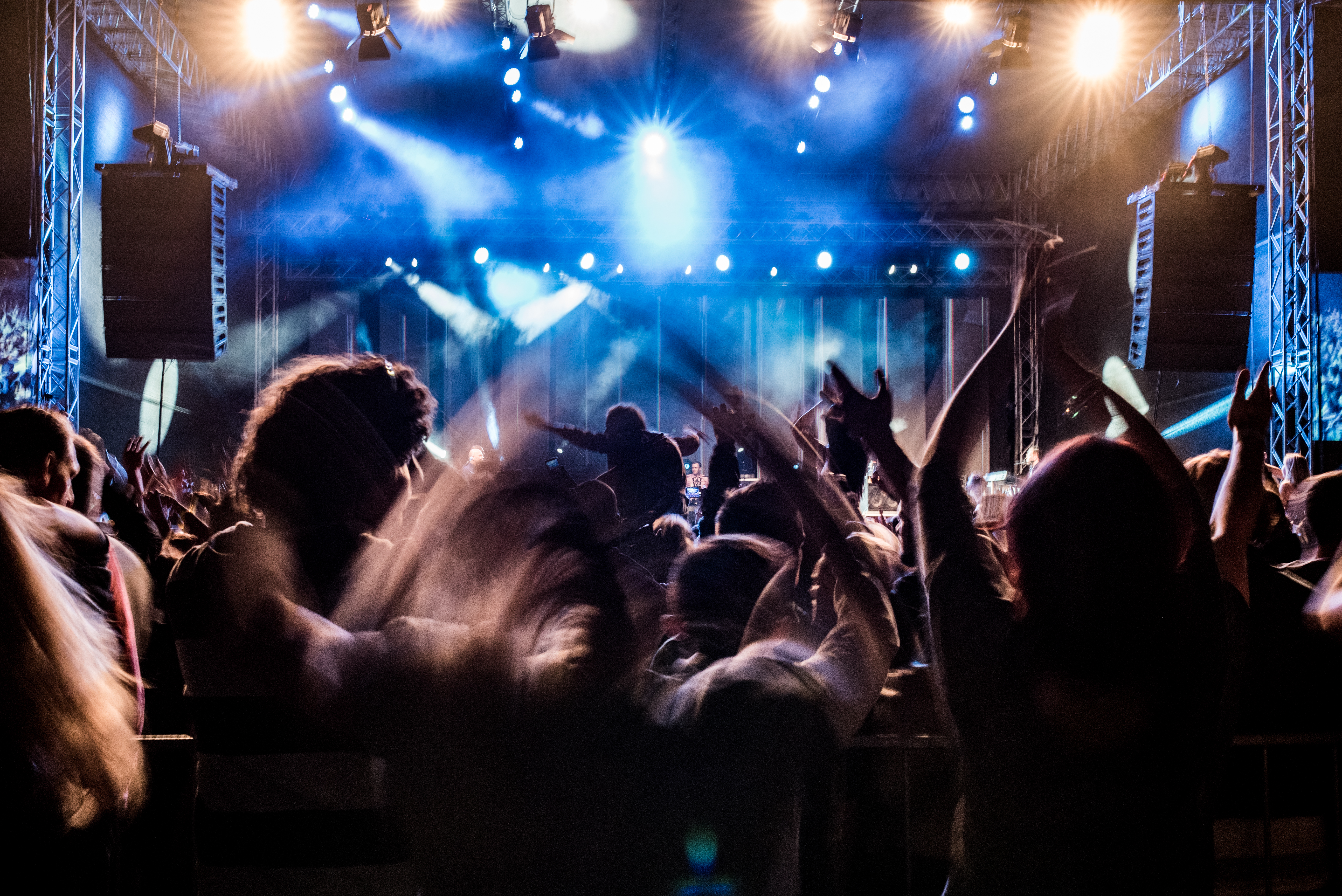 Fans with raised arms enjoying concert, people on open-air music festival