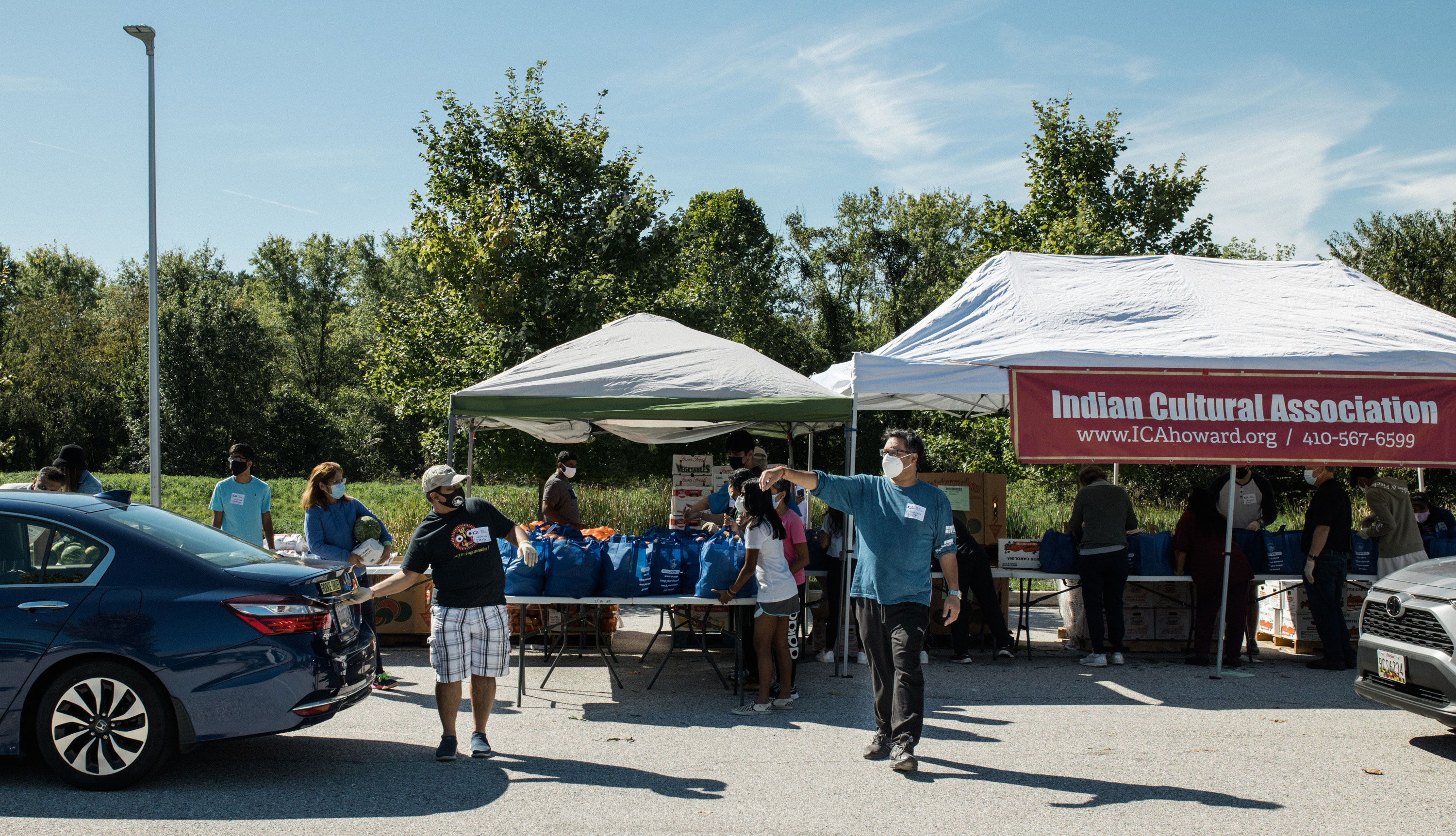 People distributing bags of food in a parking lot