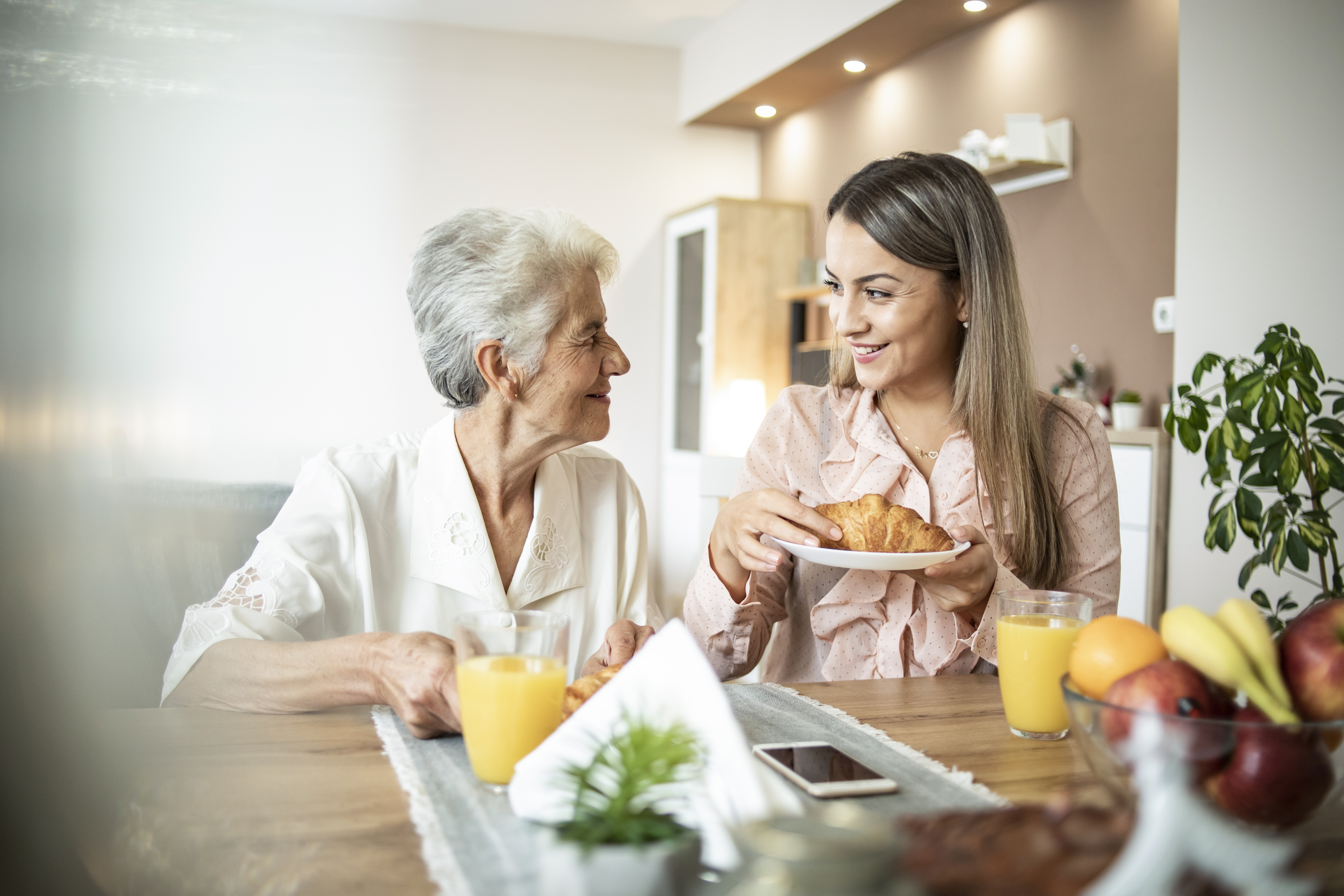 A cheerful young girl serves breakfast to her grandmother at home