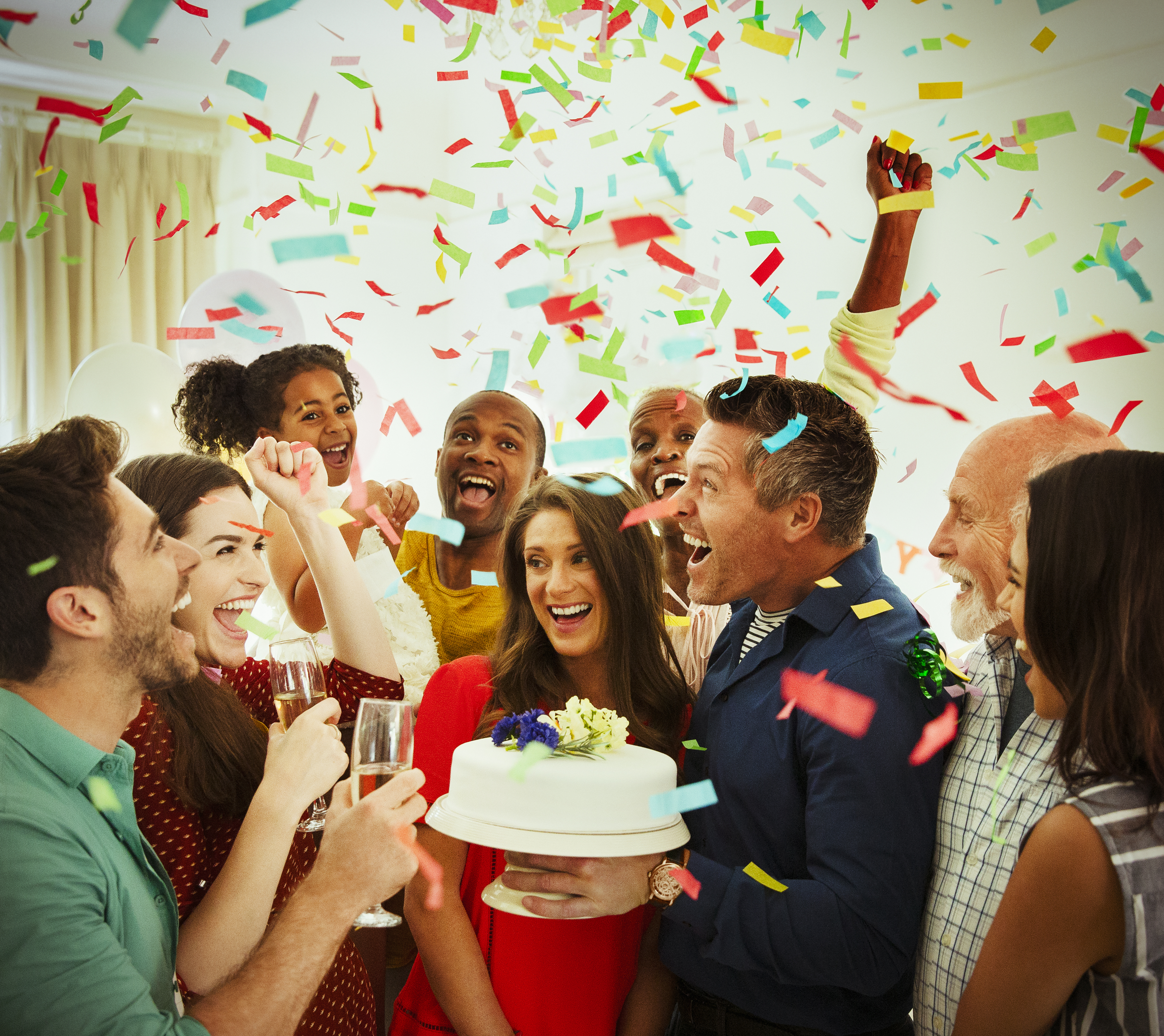 Enthusiastic family with birthday cake throwing confetti