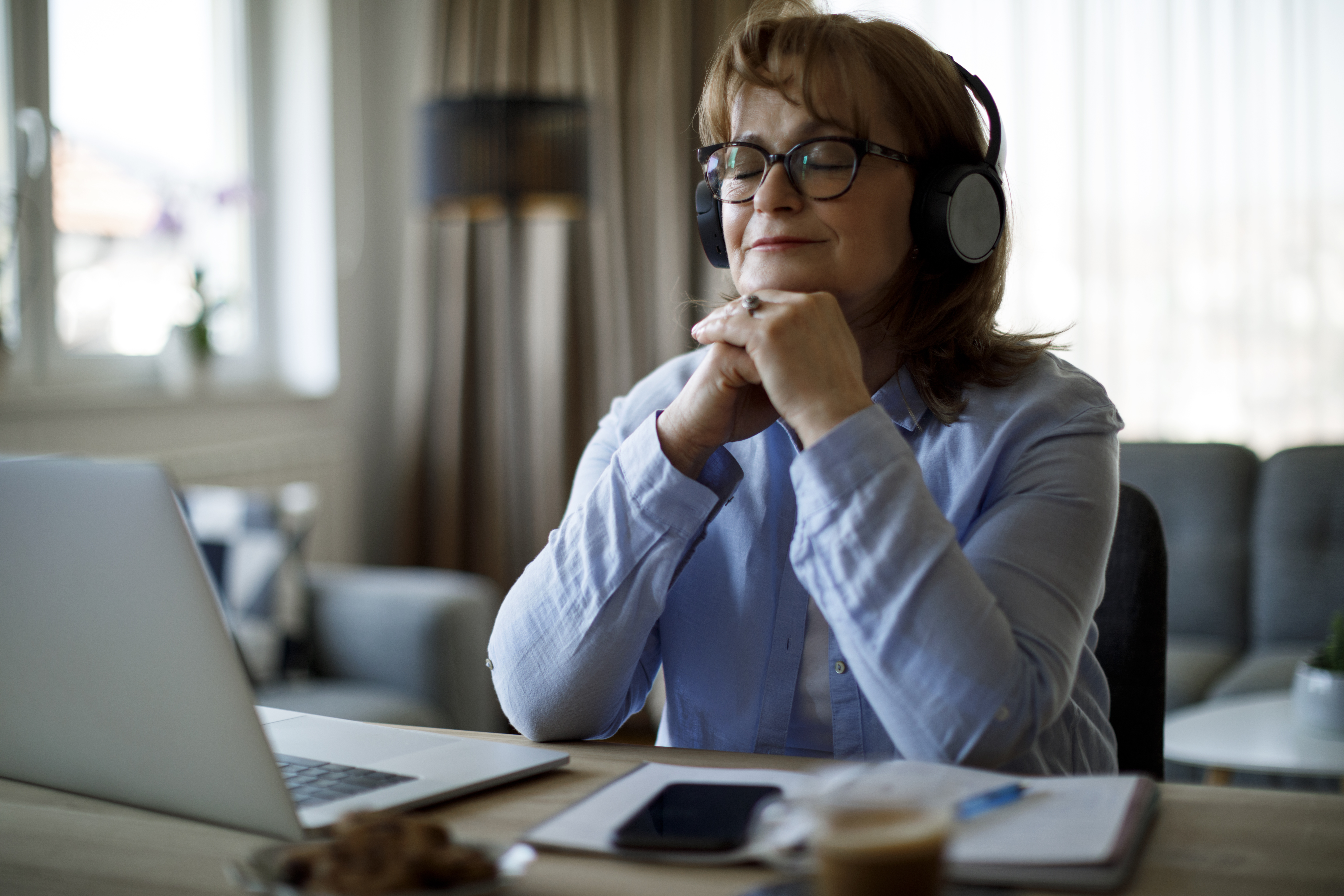 Smiling senior woman with wireless headphones enjoying music at home