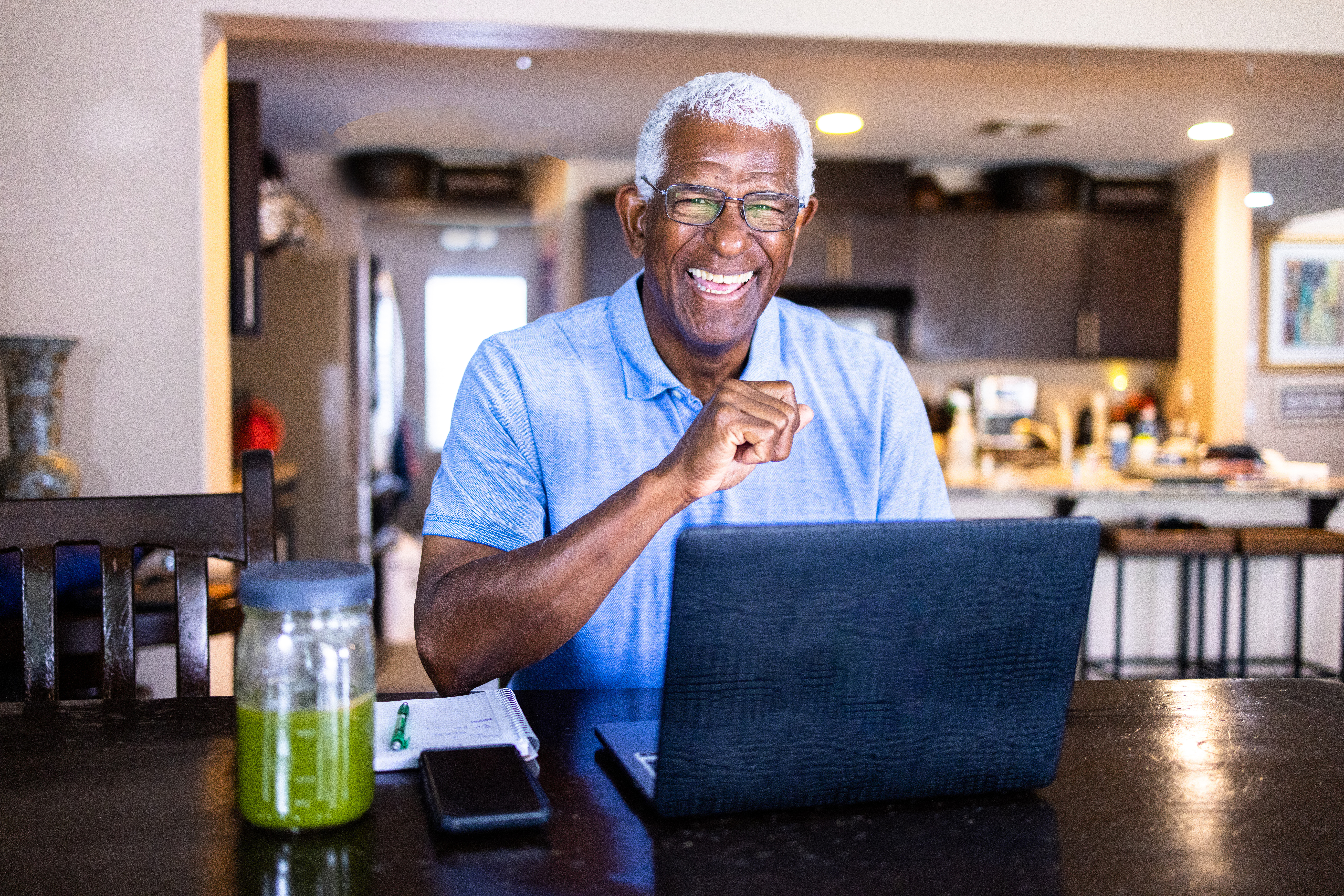 Senior Black Man Working at Laptop at Dining Table