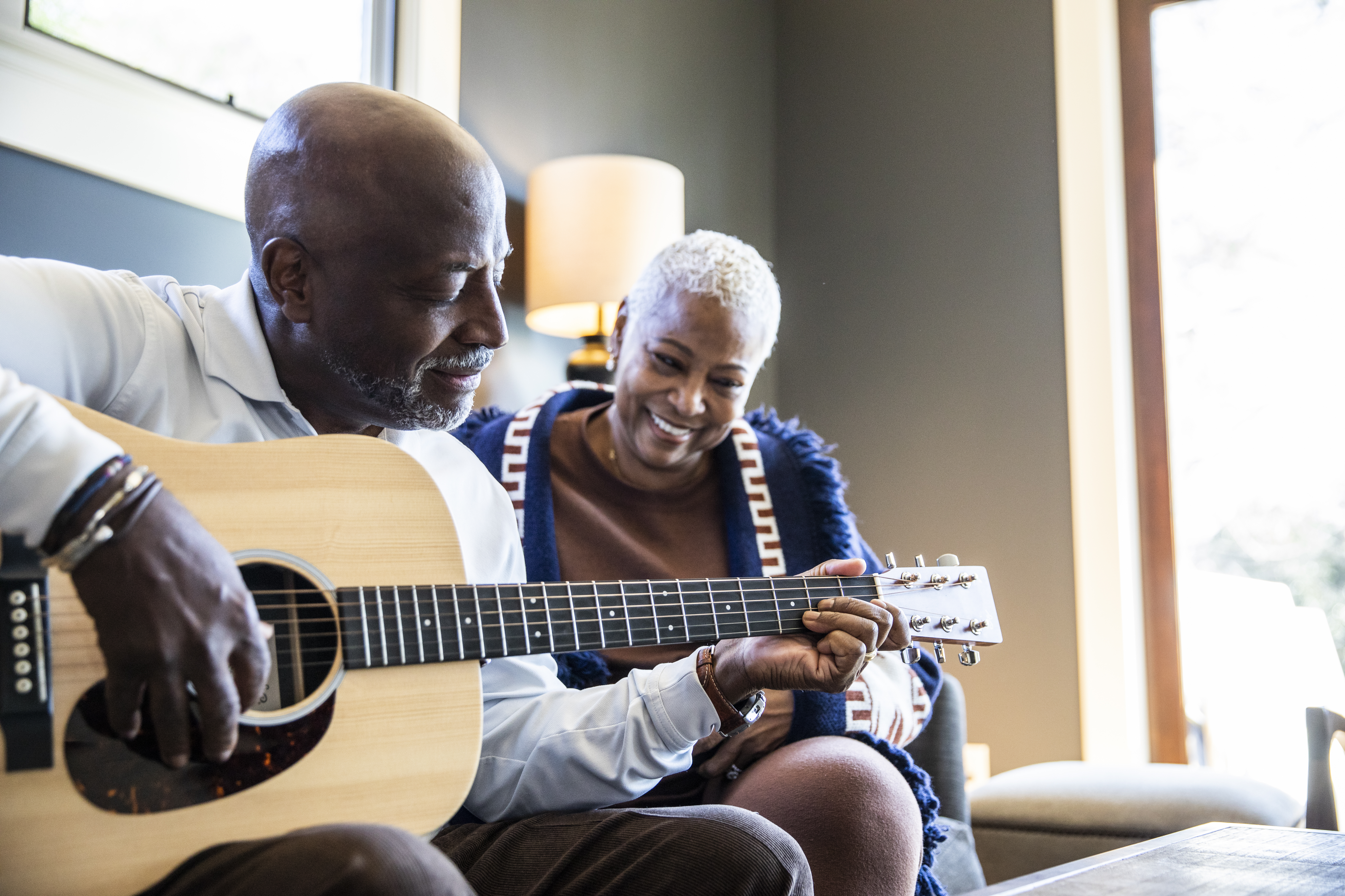 Senior man playing acoustic guitar for his wife at home