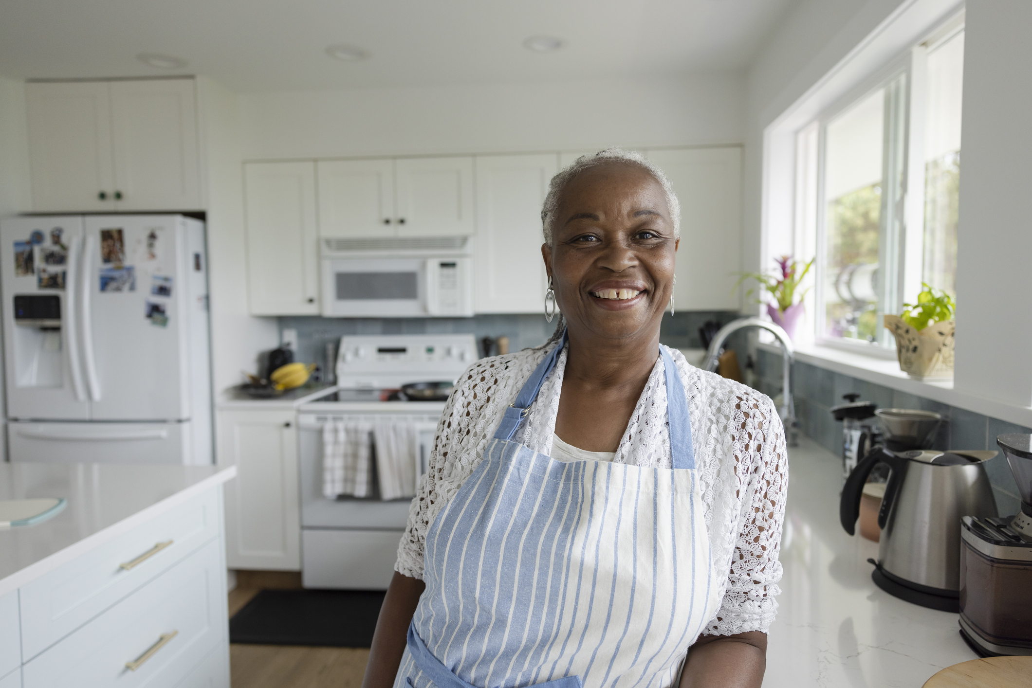 Portrait happy, beautiful senior woman in apron in kitchen at home