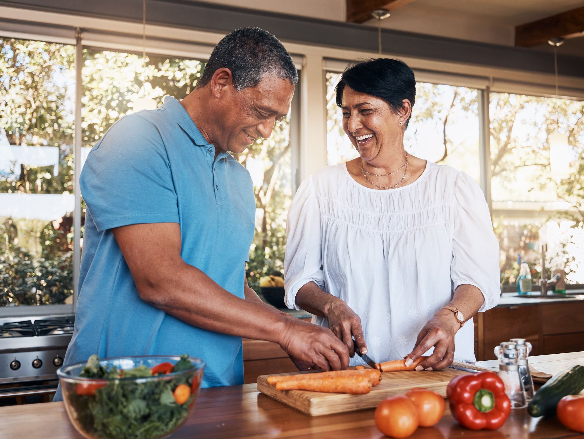 Cheerful senior couple preparing healthy meal using online recipe