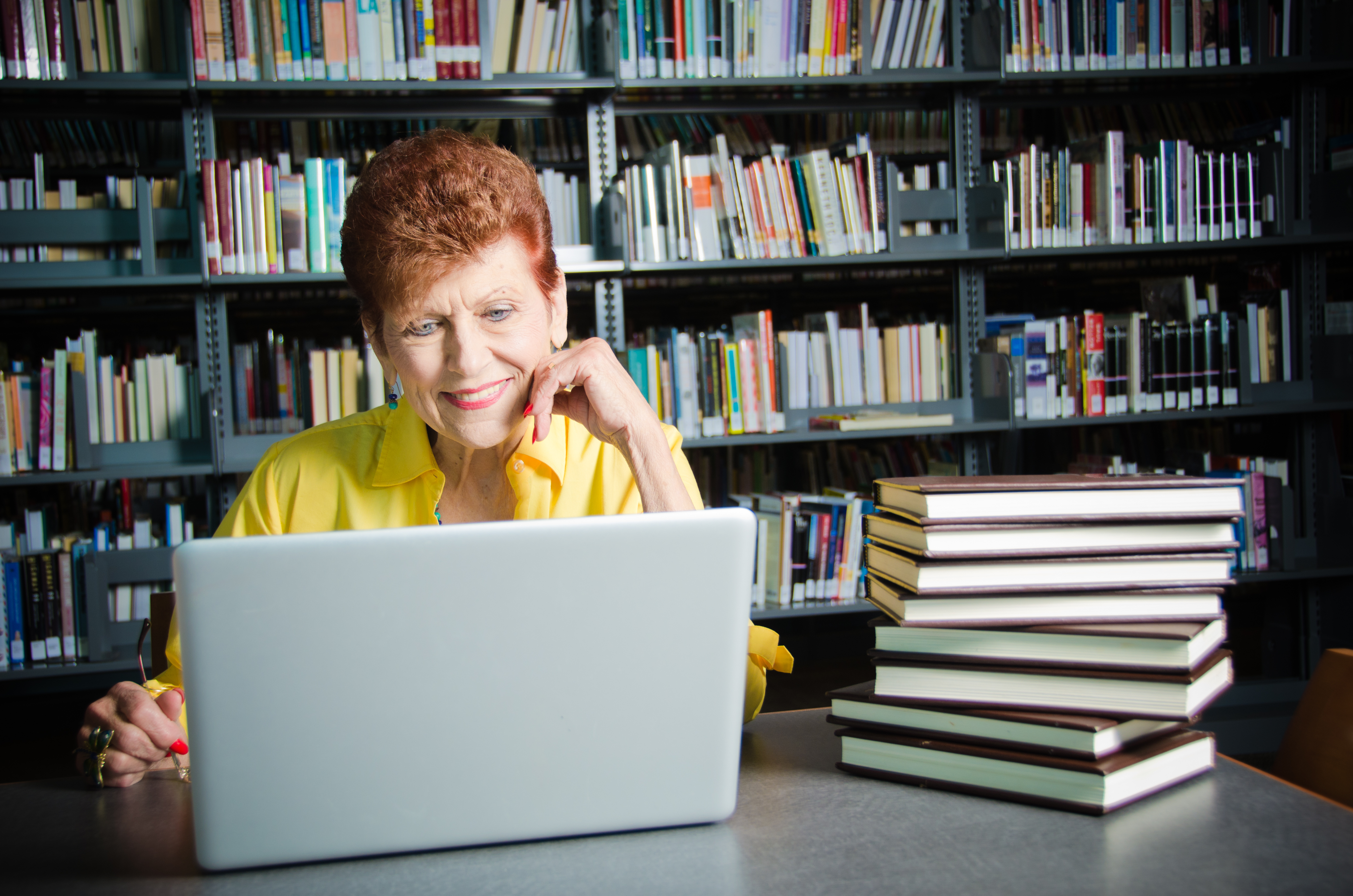 Happy Senior woman with laptop in library