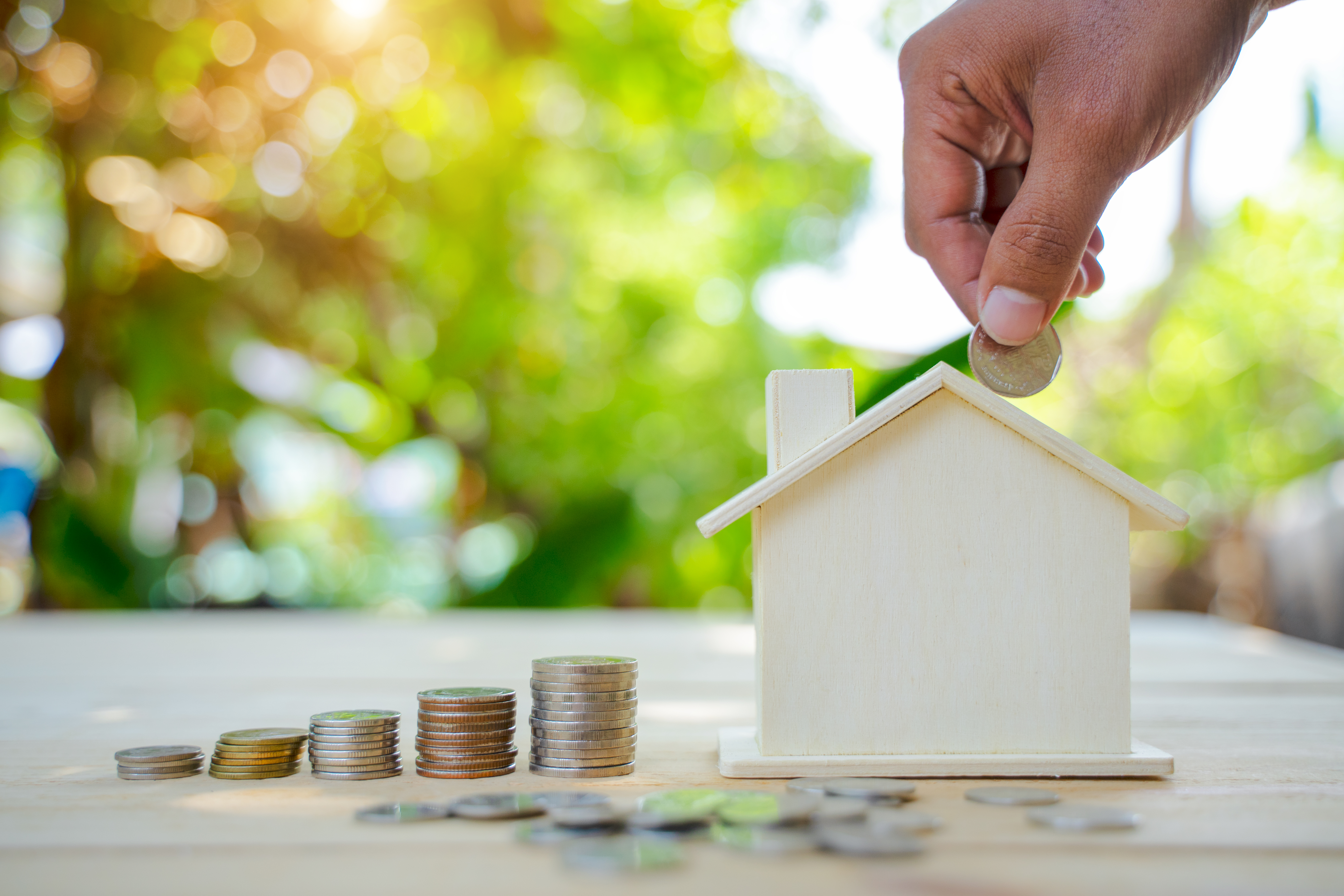 Saving money concept. House Model and Coins Stacks on wooden table. Save and investment money for prepare in the future.